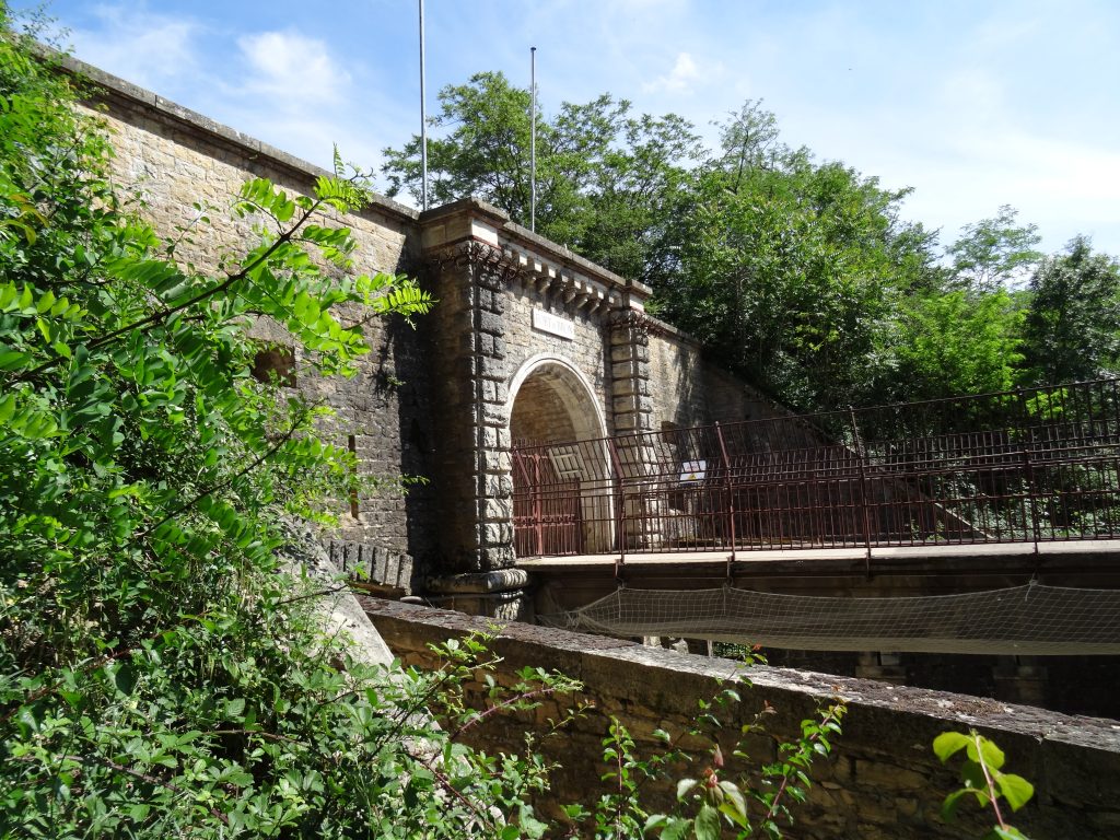 Photo prise du chemin de ronde. la photo montre la façade de l'entrée de profil en saillie sur la courtine. Le pont dormant et sa balustrade visibles au dessus du fossé.