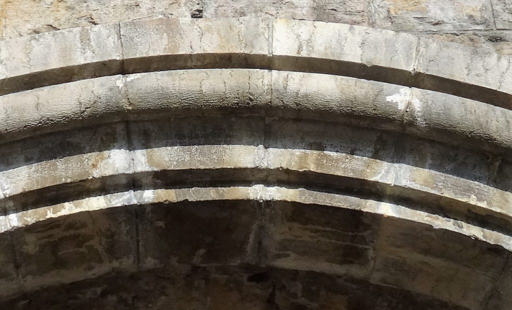 La photo fait un gros plan sur Les pierres taillées en rouleau de la partie supérieure de l'arc en plein cintre.