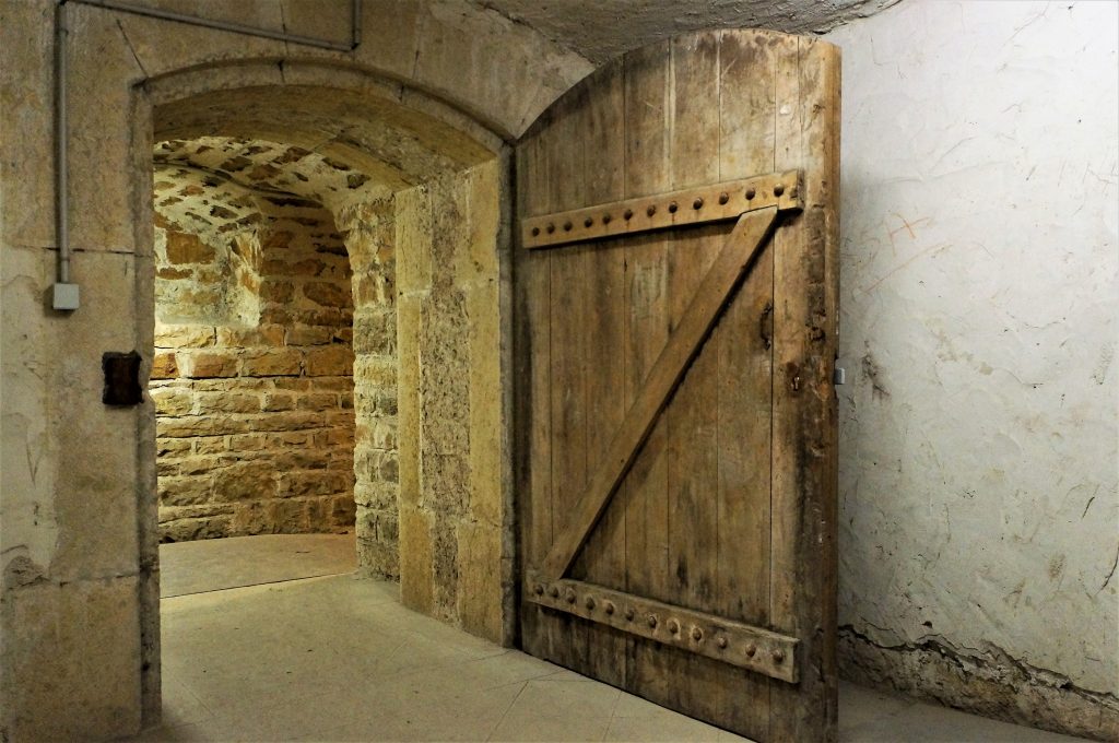 Porte d’accès  au vestibule ouverte. Dans le fond une niche est présente dans le couloir d’assainissement.