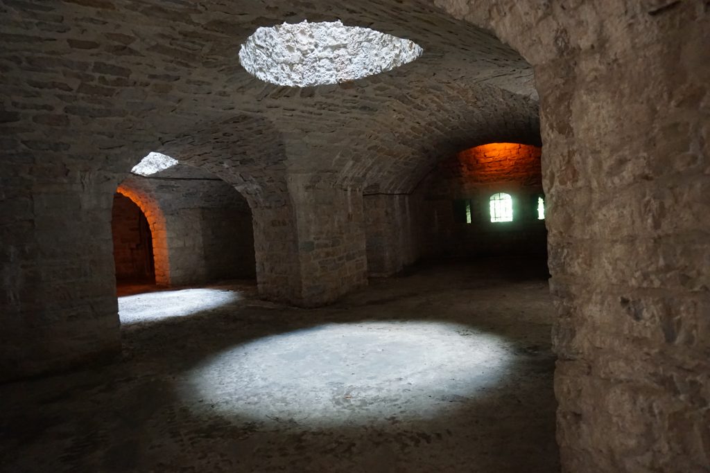la double  caponnière du fort de Bron montre des voutes en berceau. Au plafond, la lumière est apportée par de grandes ouvertures ronde. Sur le mur du fond on aperçoit les embrasures donnant sur le fossé diamant.