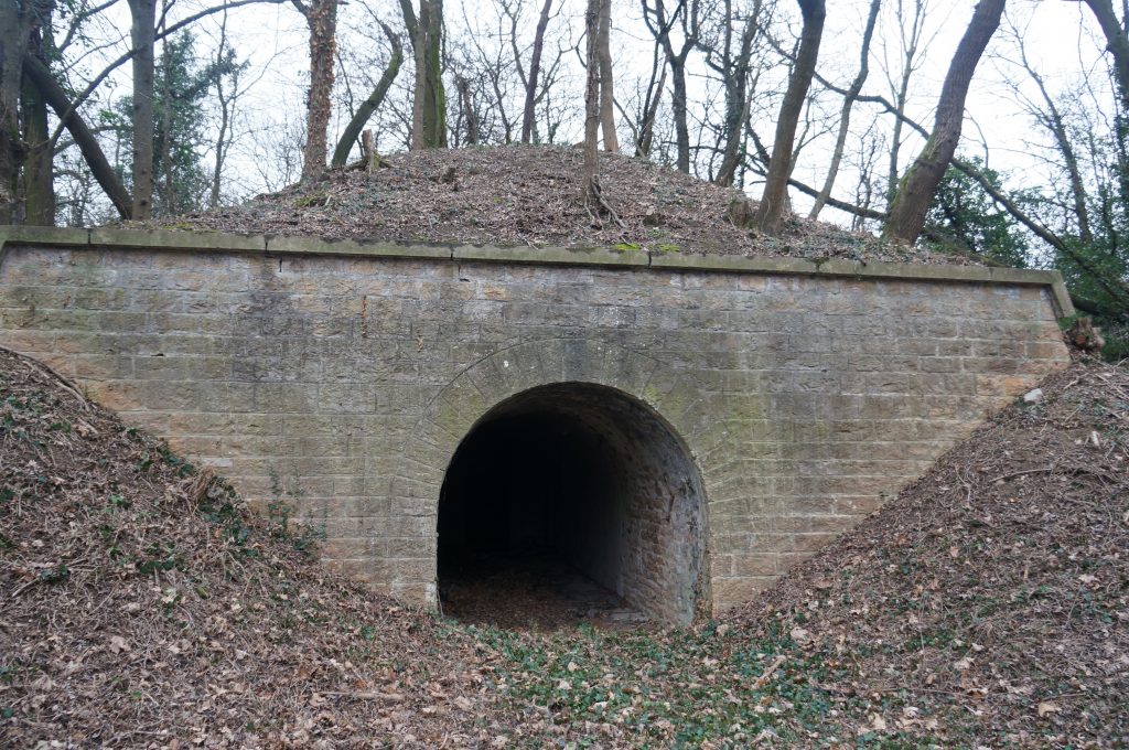 Façade maçonnée à l'arrière d'une traverse-abri du Fort de Bron, la traverse-abri  est recouverte  par une masse de terre.